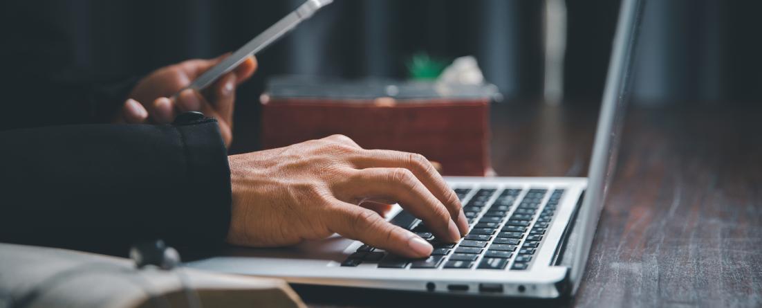 Plateforme pros-consulte Une personne sur son ordinateur, téléphone à la main