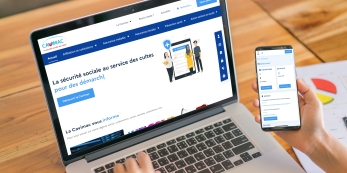 ordinateur portable avec la page d'accueil du site internet de la Cavimac et une main tenant un smartphone